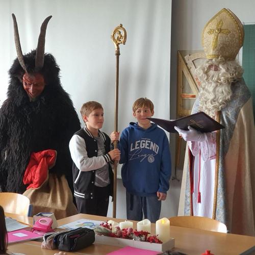 Das Bild zeigt den Nikolaus, den Krampus und zwei Schüler, die den Nikolausstab halten