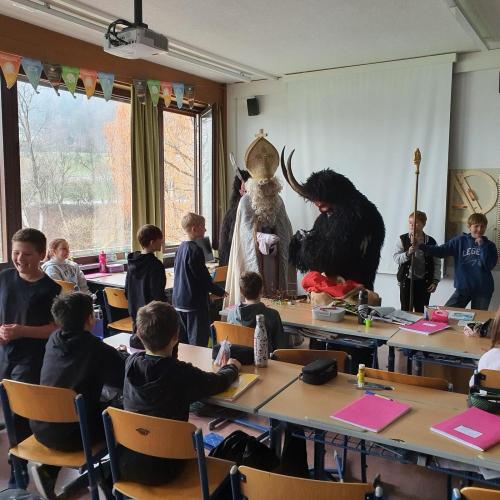 Das Bild zeigt den Nikolaus und einen Krampus in einer Klasse