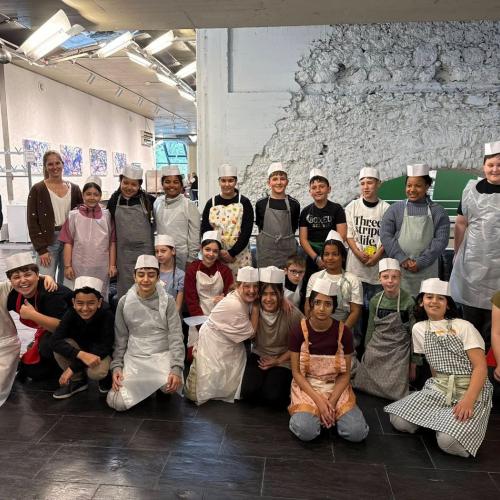 Das Bild zeigt die Schüler*innen mit Schürzen und Kochmützen