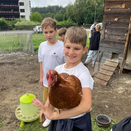 Das Bild zeigt einen Schüler mit einem Huhn am Arm