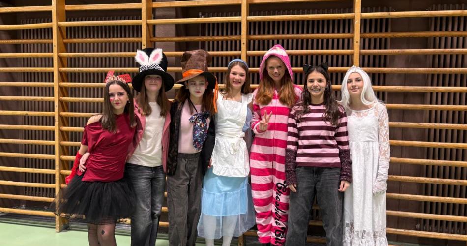 Schülerinnen und eine Lehrerin mit Kostümen aus Alice im Wunderland