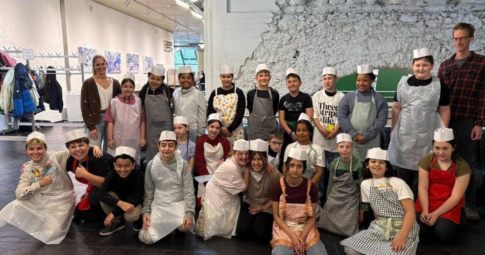 Das Bild zeigt die Schüler*innen mit Schürzen und Kochmützen