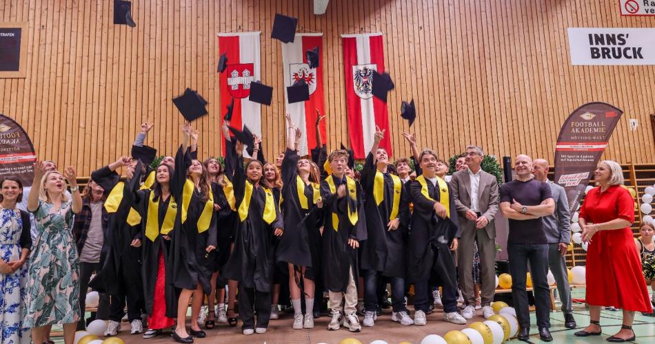 Die ist ein Gruppenbild der Klasse, während die AbsolventInnen die Hüte hochwerfen